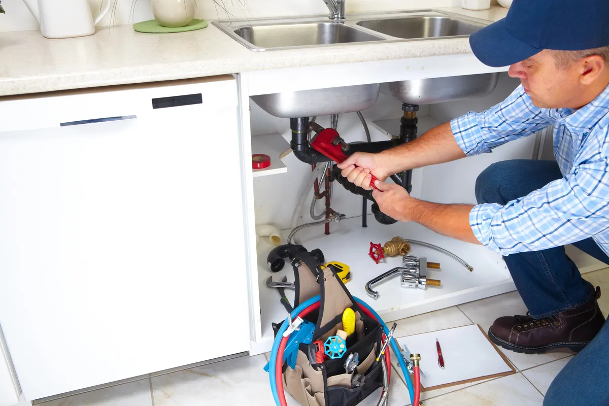 Artisan plombier en intervention : réparation d'une fuite sur canalisation